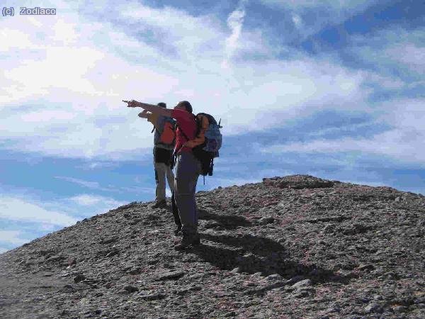 Javier señalando a América. Detrás alguien irreconocible, y Anto, en la cima del Montgrós